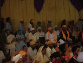 Attendees sitting on chairs in front of Parkash of Guru Granth Sahib