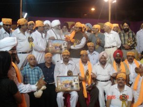 Chaman Lal handing out images of a Hindu deity , Sri Harmandir Sahib and Guru Nanak Dev Ji