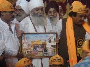 Chaman Lal handing out images of a Hindu deity , Sri Harmandir Sahib and Guru Nanak Dev Ji