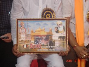 Chaman Lal handing out images of a Hindu deity , Sri Harmandir Sahib and Guru Nanak Dev Ji